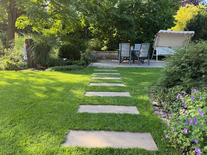 Trittplattenweg im Rasen führt zur Gartenterrasse